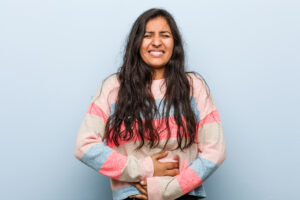 New mother holding her stomach, symbolizing postpartum gut health and digestion recovery after childbirth.