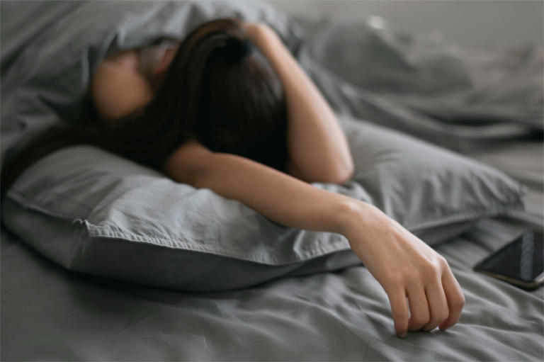 Woman lying awake in bed at night, symbolizing postpartum insomnia and the challenge of getting sleep even when her baby is asleep
