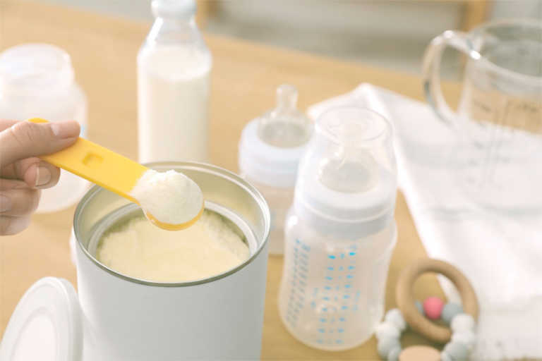 Close-up of a hand scooping formula powder from a container, symbolizing the scrutiny of formula feeding versus breastfeeding in India."