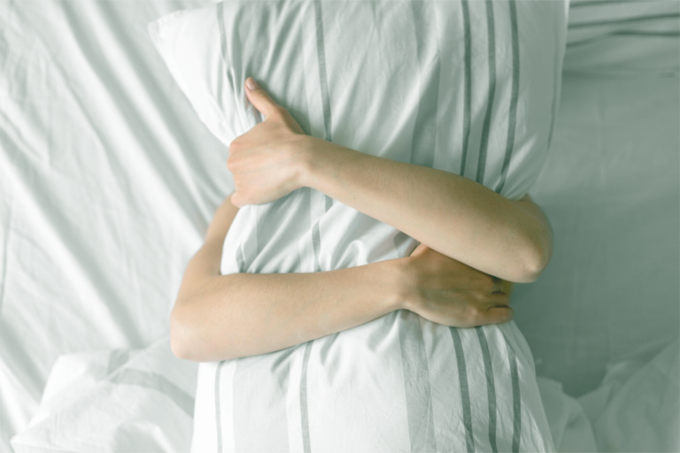 Woman hugging a pillow, looking uncomfortable, symbolizing postpartum pain during sex and recovery guidance
