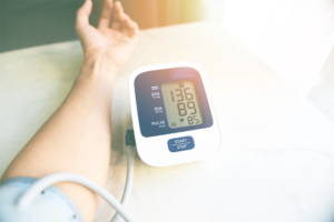 Hand measuring blood pressure with a digital monitor showing high readings, highlighting postpartum hypertension management tips.